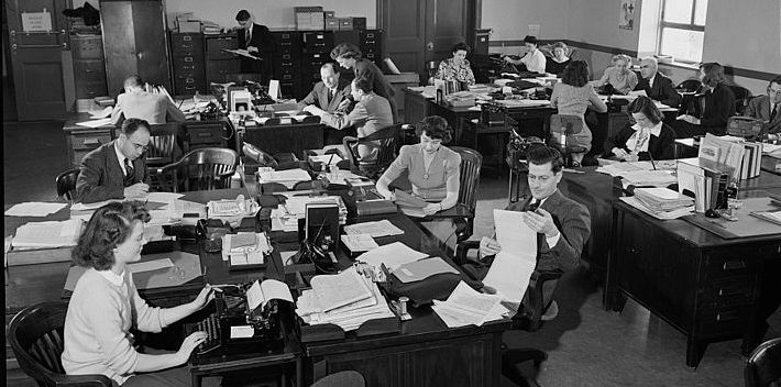a picture of people doing important things in an office setting ca. 1943.